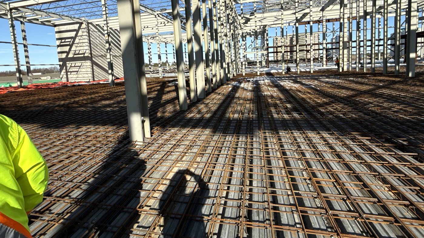 Interior of a cinema under construction, showing dense structural steel framing, open-web joists and reinforcing steel.