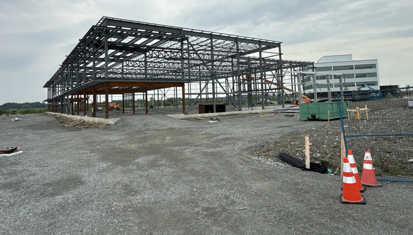 Structural steel frame of a single-storey commercial building under construction on a gravel site.