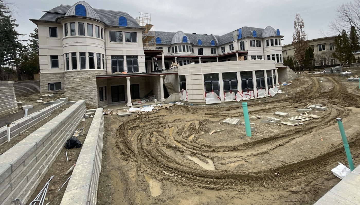 A large custom house under construction, stone-clad with a turret, before landscaping.