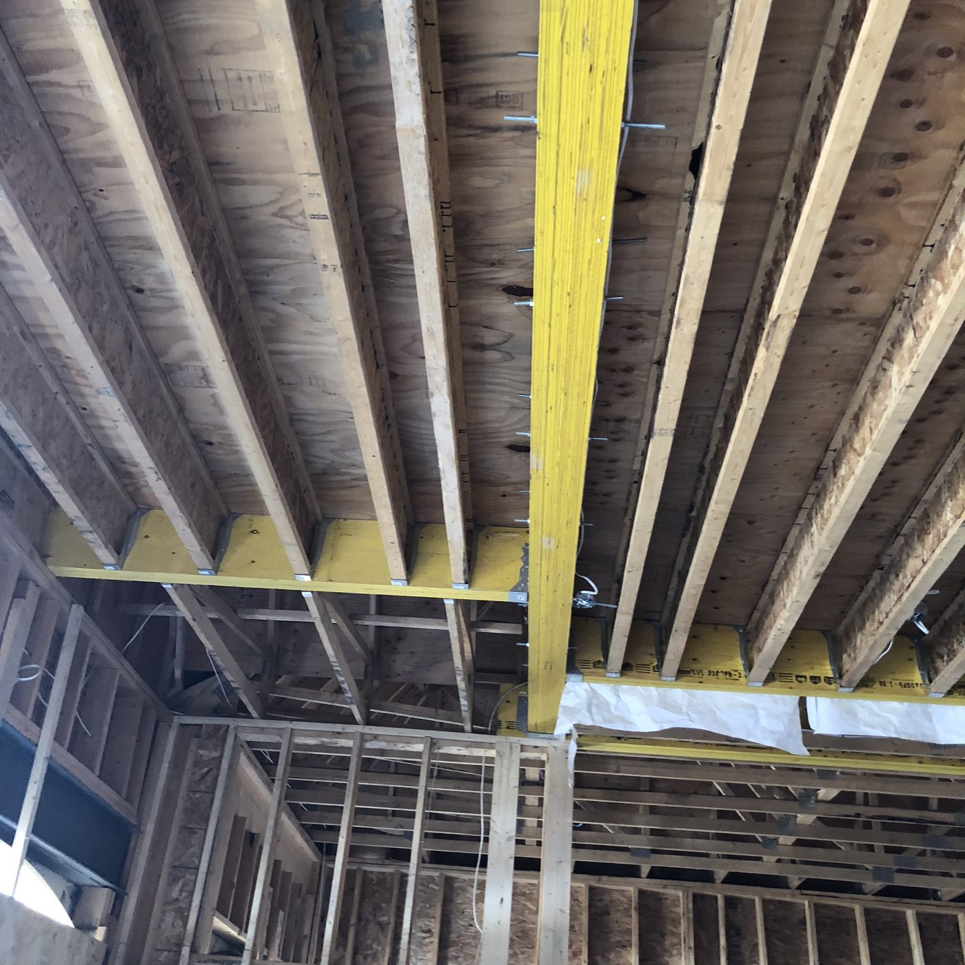 Engineered wood floor joists and laminated veneer lumber beams seen from below during framing.
