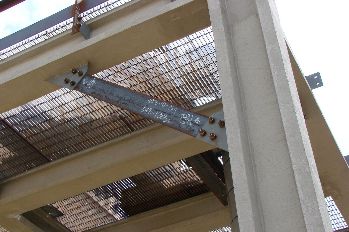 Bolted steel bracing member connected to a concrete column, with grating floors above.