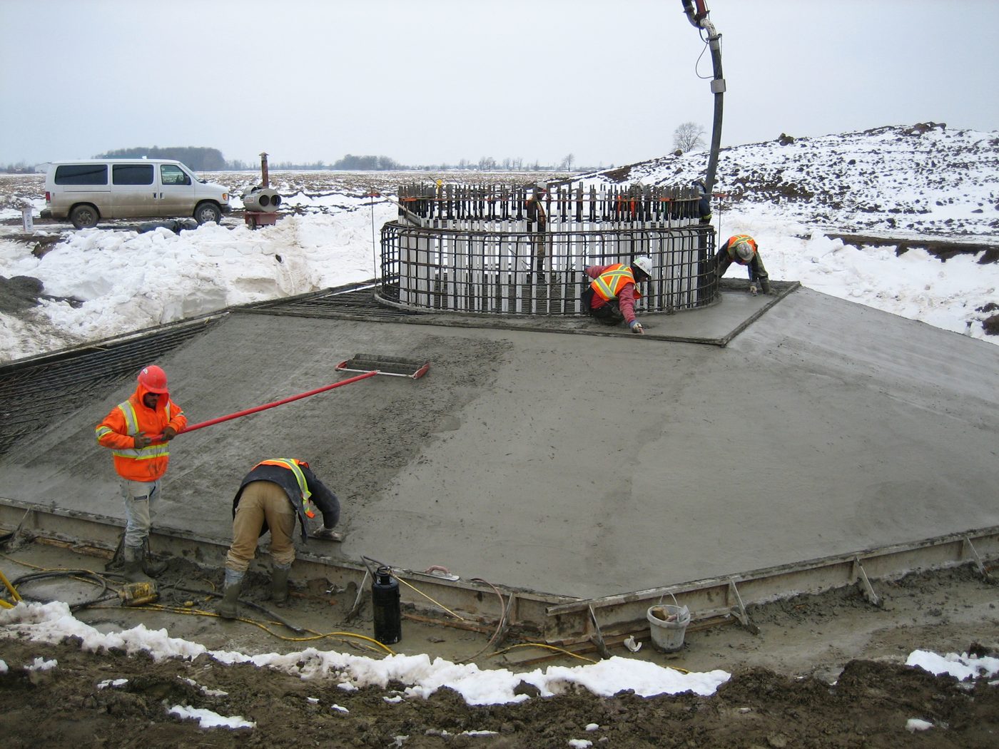 Crew finishing the concrete of an octagonal wind turbine foundation with the anchor cage set in the centre.
